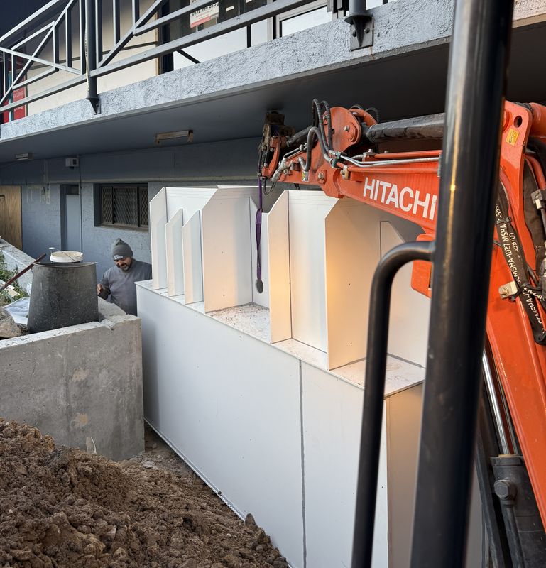 Excavator working beside a building with new pits installed