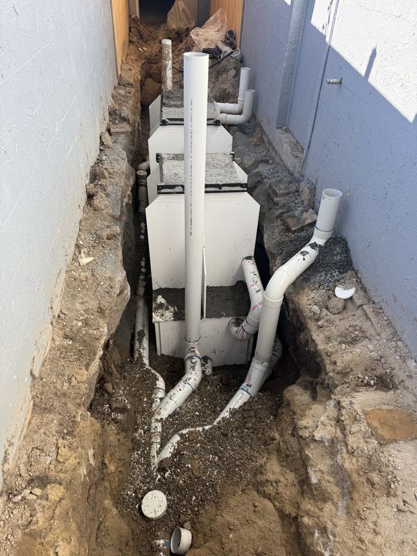 Drainage pits and pipework installed in a tight-access excavation between buildings